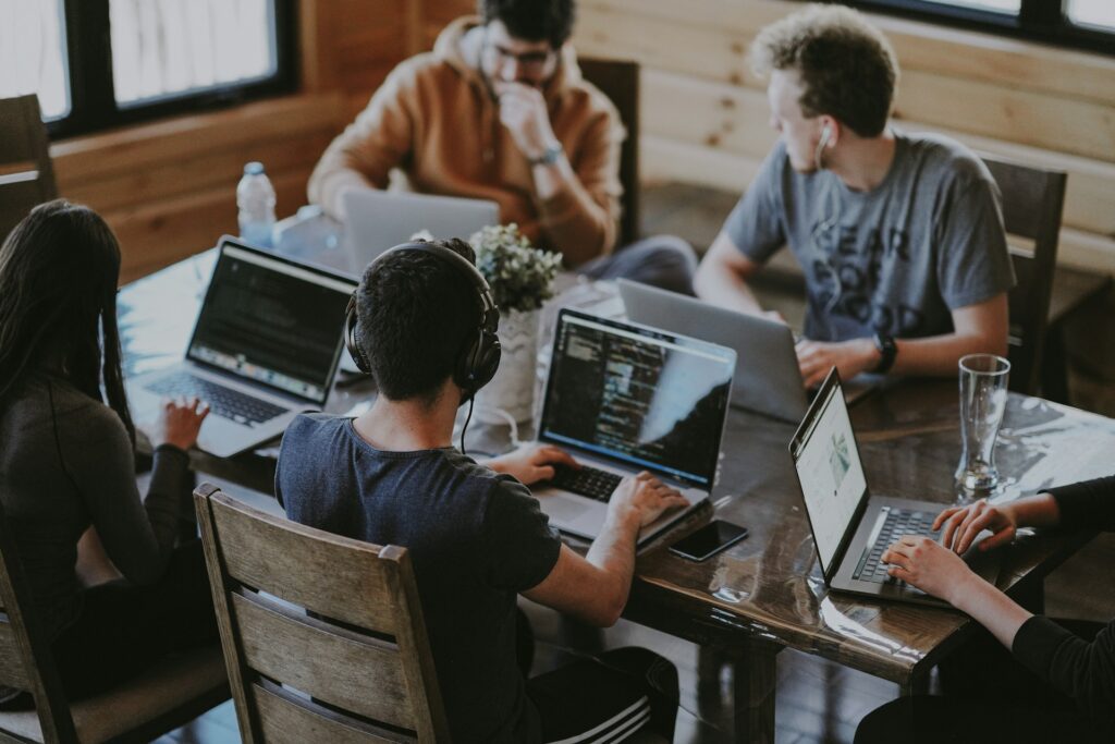 a group of people sitting around a table with laptops working on website design