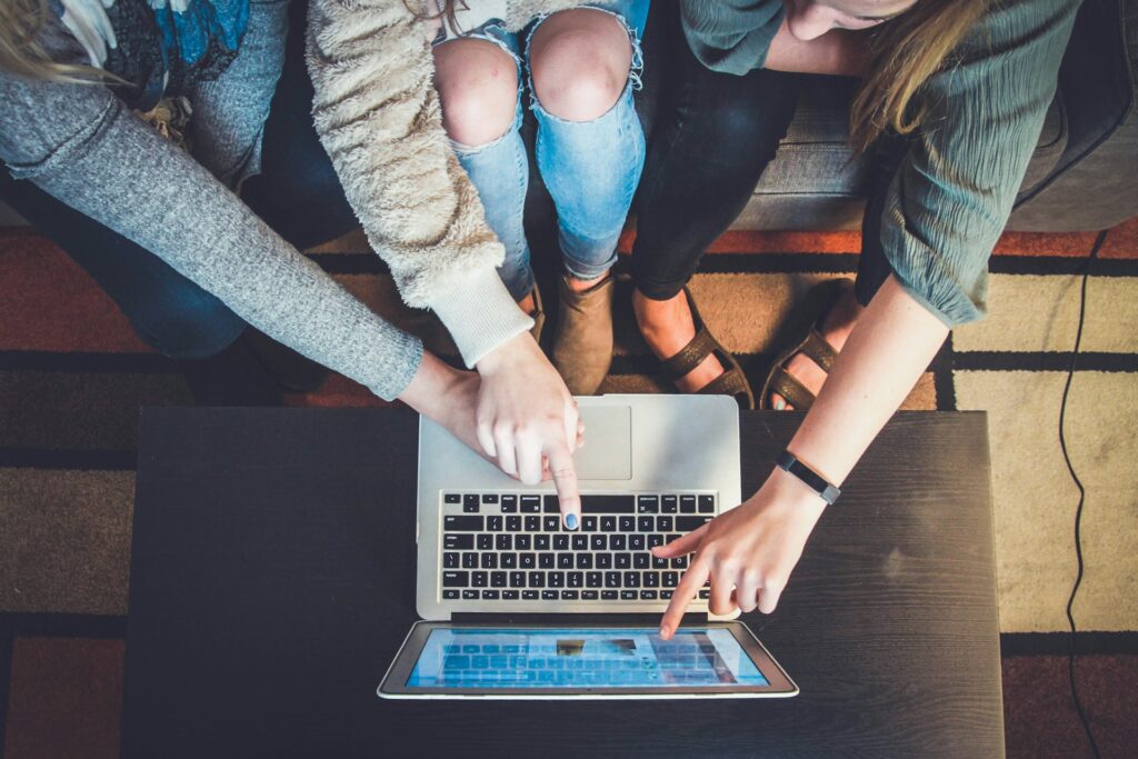 A group of people pointing at a laptop discussing a website design